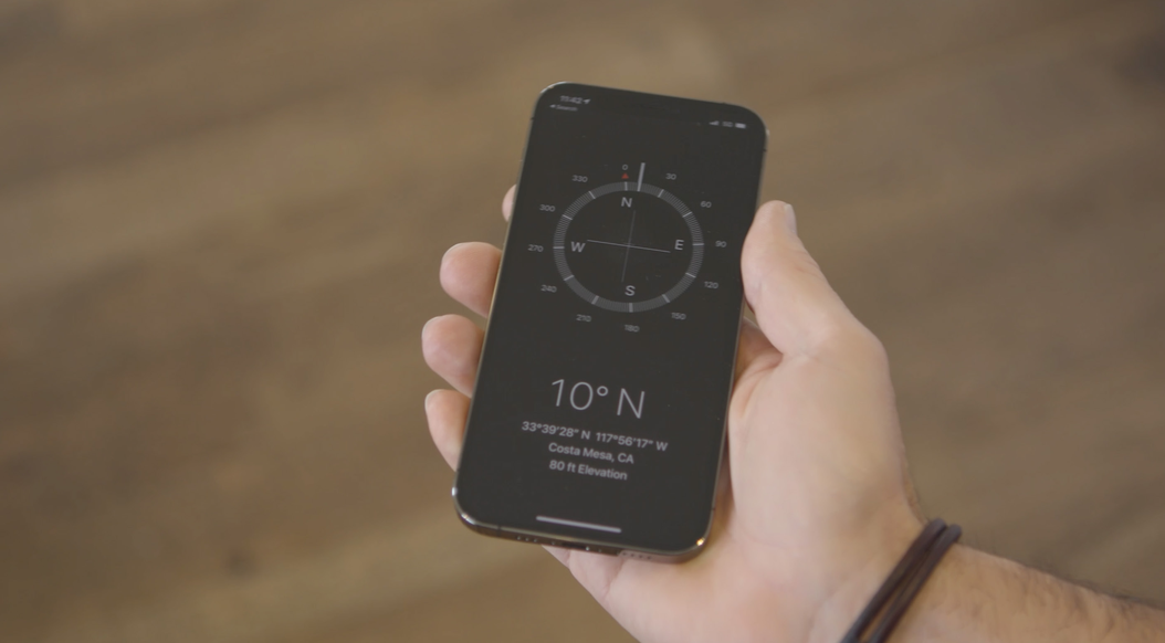 A hand holding a phone with a compass app showing 10 degrees north
